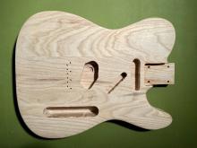 top view of guitar body routed and cut out from wood